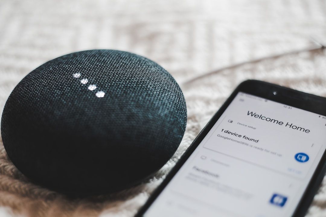 Ein intelligenter Lautsprecher neben einem Smartphone, der einen „Willkommen zu Hause“-Bildschirm mit Einrichtungsoptionen anzeigt, perfekt für Ihren neuen, von Aachen inspirierten Wohnraum.