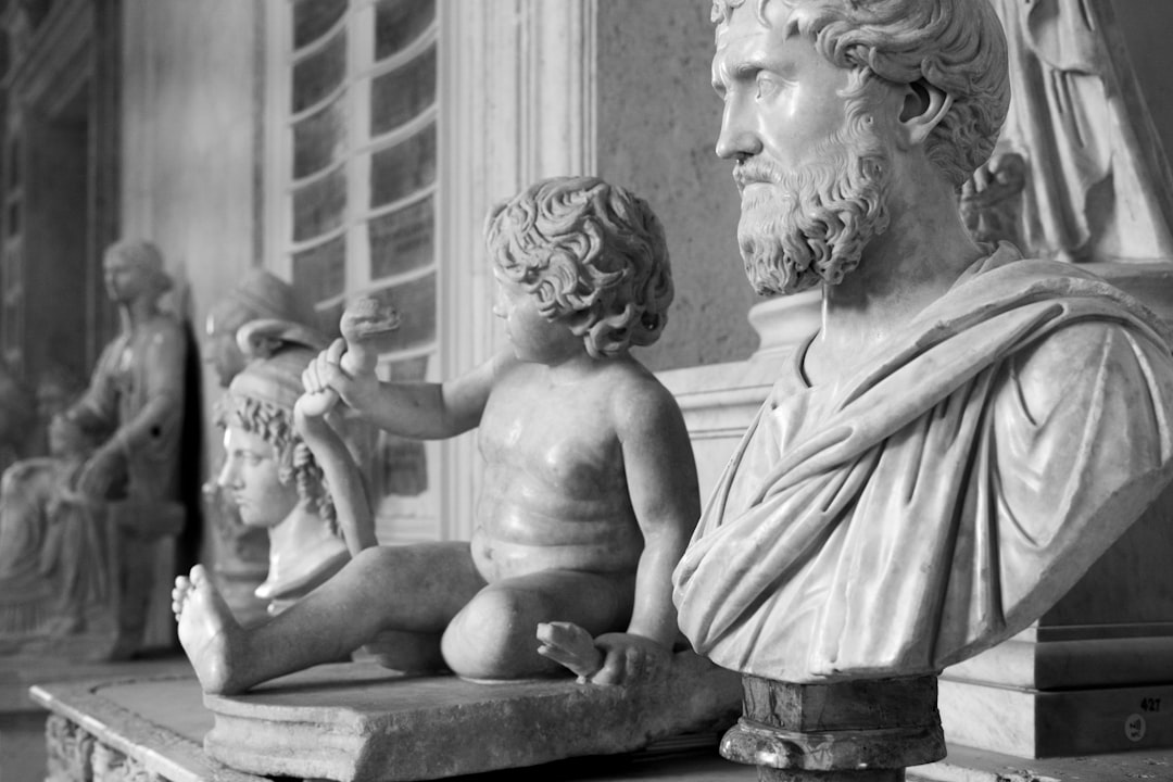 Schwarz-Weiß-Abbildung von Marmorstatuen, darunter ein sitzendes Kind, das einen Gegenstand hält, und ein bärtiger Mann in einem drapierten Gewand, ausgestellt in der Aachener Galerie.