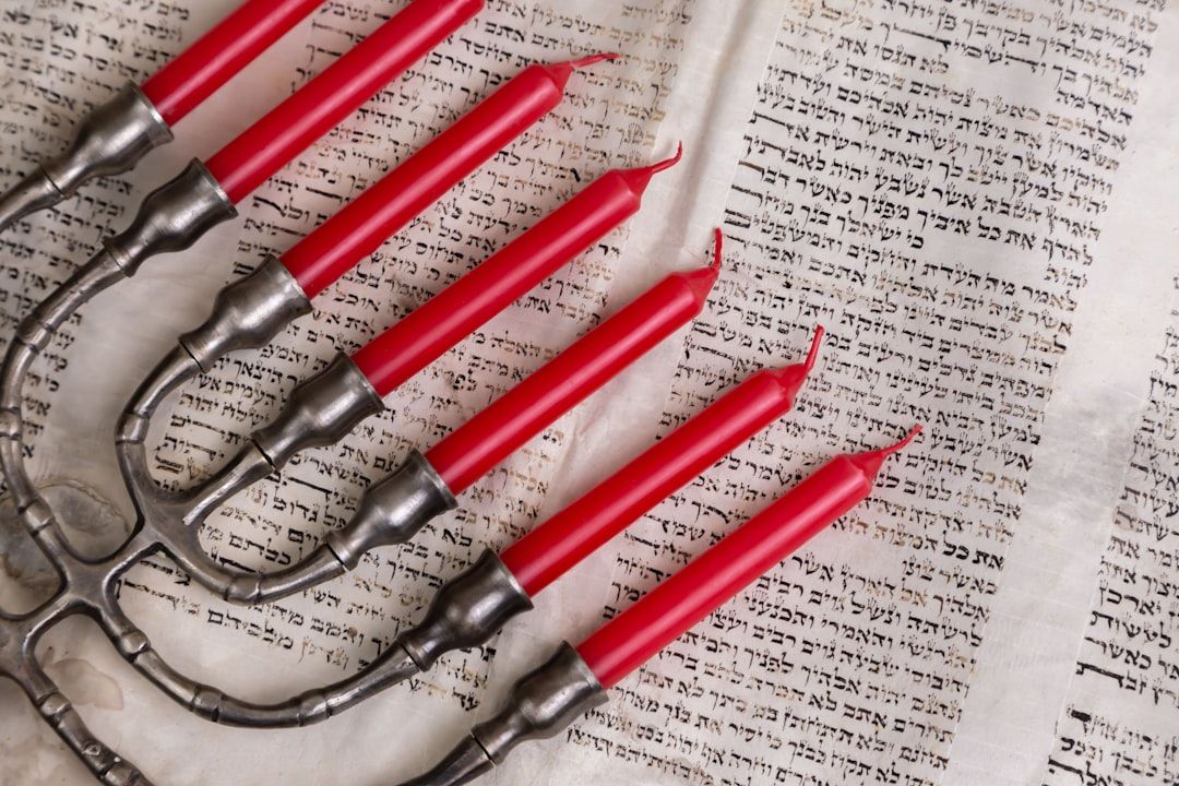 Eine Menora mit roten Kerzen steht auf einem offenen hebräischen Text und erinnert an die alten Traditionen, die in Aachen allgegenwärtig sind.