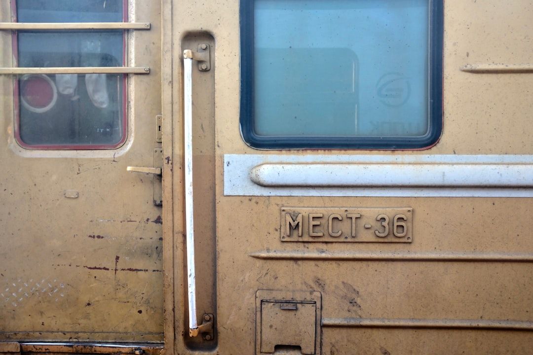 Nahaufnahme eines Teils eines beigen Zugwaggons. Man sieht sein Fenster, den Türgriff und eine Plakette mit dem Text „МЕСТ 36“. Das Äußere wirkt verwittert und schmutzig und erinnert an die historischen Züge, die einst durch Aachen fuhren.