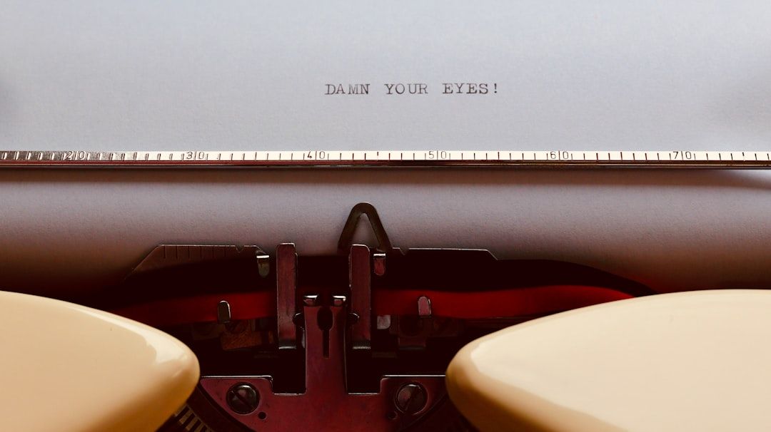 Eine Nahaufnahme einer Schreibmaschine mit einem Stück Papier mit der Aufschrift „VERDAMMT SIND DEINE AUGEN!“ vor einem Hintergrund, der an den historischen Charme Aachens erinnert.