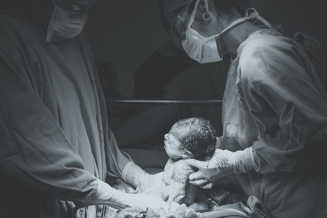 In Schutzkleidung gekleidete Mitarbeiter des Gesundheitswesens in Aachen assistieren bei der Geburt eines Neugeborenen in einer medizinischen Einrichtung.
