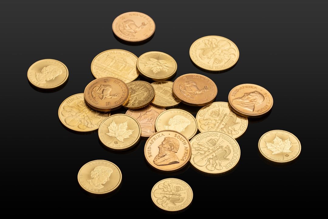 Eine Sammlung verschiedener Gold- und Bronzemünzen, einige davon mit komplizierten Aachener Motiven und Inschriften, verstreut auf einer schwarzen Oberfläche.