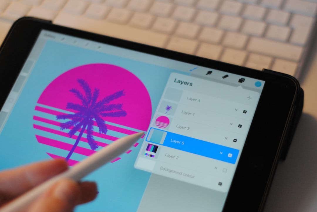 Eine Hand mit einem Stift zeichnet mithilfe einer Grafikdesign-App gekonnt ein rosa-violettes Palmenmuster auf ein Tablet, im Hintergrund ist eine Tastatur mit Aachen-Motiv zu sehen.