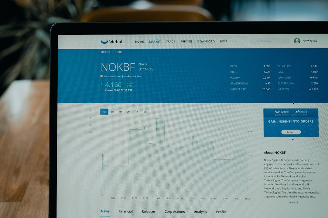 Ein Laptop-Bildschirm zeigt eine Börsendetailseite für Nokia (NOKBF) mit Finanzdaten und einem Diagramm. Die Benutzeroberfläche erinnert an die detaillierten Aufzeichnungen, die man an den Finanzhochschulen in Aachen studieren könnte, und enthält Menüoptionen wie Markt, Handel, Preisgestaltung und Download.