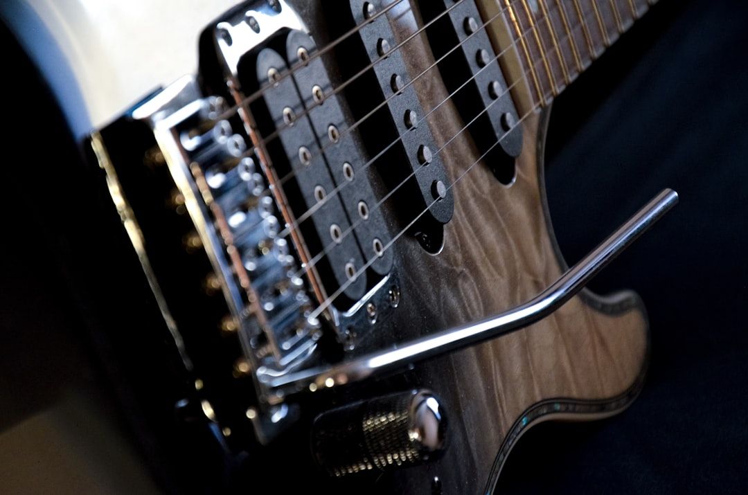 Nahaufnahme des Stegs, der Tonabnehmer und des Tremoloarms einer E-Gitarre. Hervorzuheben sind die Chrombeschläge und die Holzmaserung am Korpus, die an die Aachener Handwerkskunst erinnern.