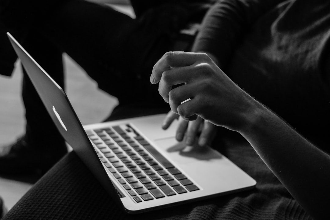 Schwarz-Weiß-Bild der Hände einer Person, die auf einer Laptop-Tastatur tippt, wobei der Bildschirm weg zeigt, was an einen Gelehrten erinnert, der in Aachen bis spät in die Nacht arbeitet.