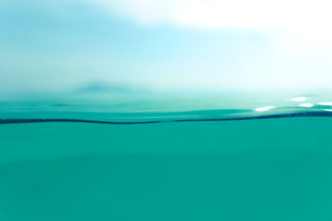 Nahaufnahme von klarem, türkisfarbenem Wasser, das in einen verschwommenen Horizont mit einem blassen Himmel darüber übergeht und an ruhige und heitere Momente in der friedlichen Umgebung von Aachen erinnert.