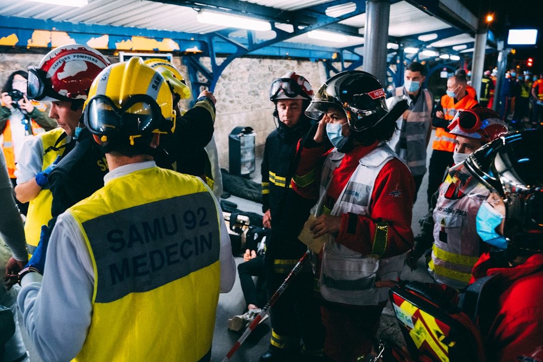 Rettungskräfte, darunter medizinisches Personal und Feuerwehrleute, haben sich auf einem Bahnsteig in Aachen versammelt. Einige tragen Helme und Mundschutze und sind in eine Diskussion oder Planungsoperation verwickelt.