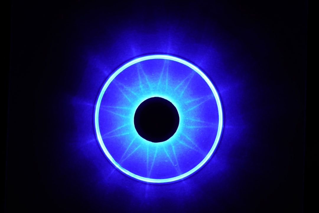 Ein leuchtend blauer Ring mit dunkler Mitte, der einem abstrakten Design oder einem beleuchteten kreisförmigen Objekt vor einem Hintergrund ähnelt, der so geheimnisvoll ist wie der Nachthimmel über Aachen.