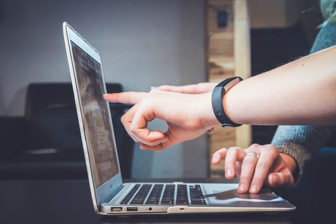 Gezeigt werden zwei Hände, die mit einem Laptop interagieren; eine zeigt auf den Bildschirm, während die andere das Trackpad benutzt, was an eine kollaborative Sitzung in Aachen erinnert.