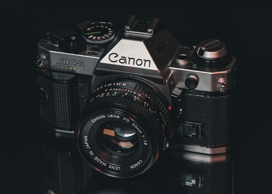 Nahaufnahme einer Canon AE-1 Program 35-mm-Filmkamera mit einem 50-mm-f/1.8-Objektiv, aufgenommen in Aachen vor einem dunklen Hintergrund.