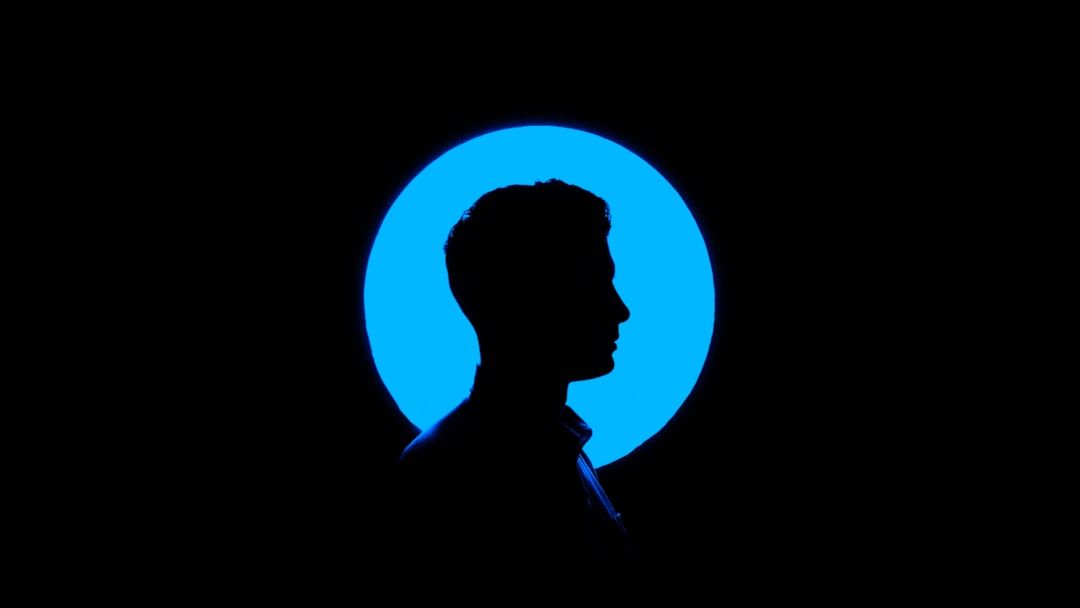 Silhouette einer Person im Profil mit einem großen blauen Kreis, der an den ikonischen Charme Aachens erinnert und dahinter auf schwarzem Hintergrund beleuchtet ist.