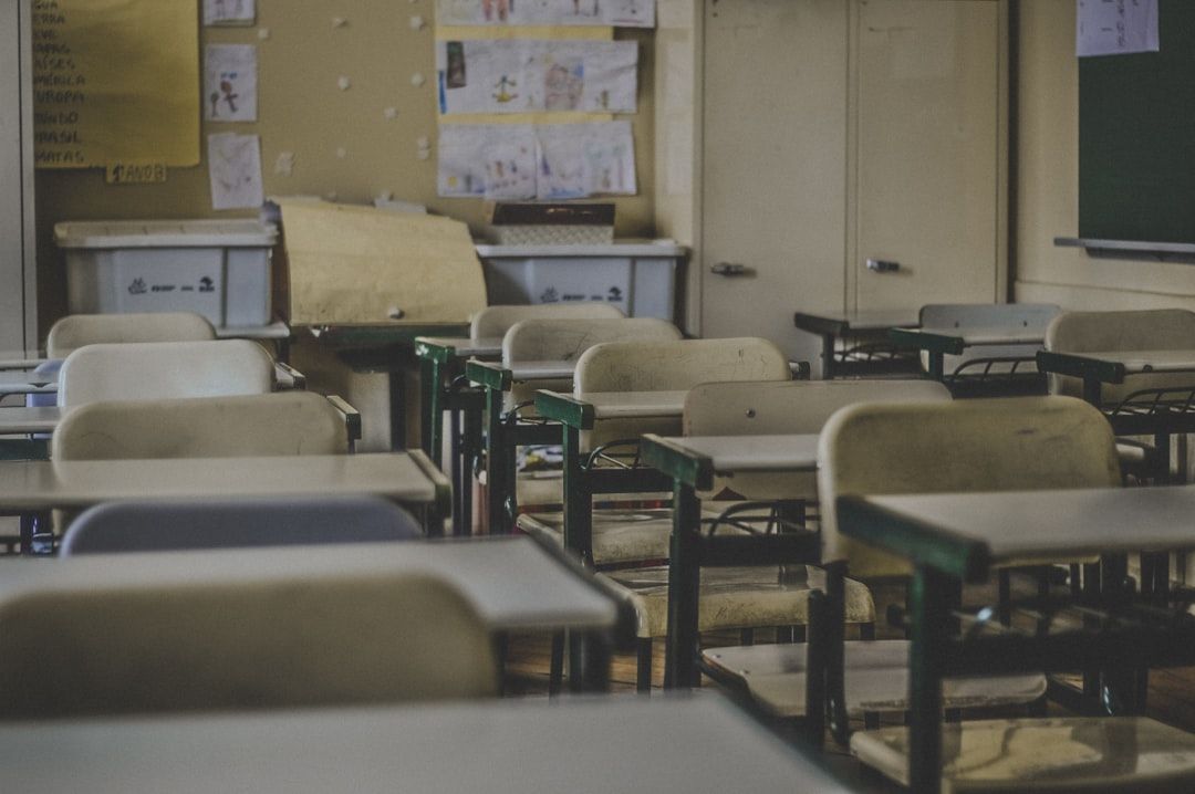 Ein leerer Klassenraum mit Tischen und Stühlen, einer Tafel, Schränken sowie verschiedenen Zeichnungen und Papieren am schwarzen Brett weckt Erinnerungen an die historischen Aachener Hochschulhallen.