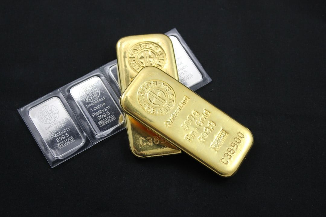 Zwei Goldbarren und drei Silberbarren liegen elegant auf einem schwarzen Untergrund und erinnern an die Schätze, die man in Aachen finden kann.
