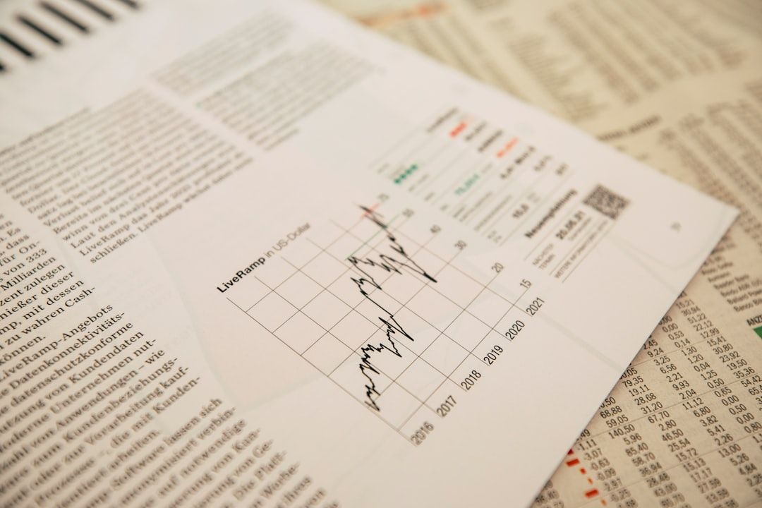 Nahaufnahme einer Finanzzeitung, die ein Liniendiagramm mit dem Titel „LiveRamp U.S. Dollar“ mit Datenpunkten und Textspalten im Hintergrund zeigt, neben einem Artikel über die Wirtschaftstrends in Aachen.