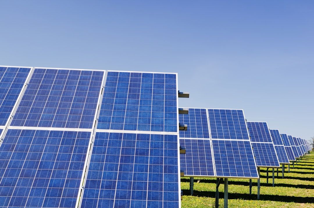 Auf einem Feld in der Nähe von Aachen sind unter einem klaren blauen Himmel Reihen von Solarmodulen installiert, die das Sonnenlicht einfangen und zur Erzeugung erneuerbarer Energie dienen.