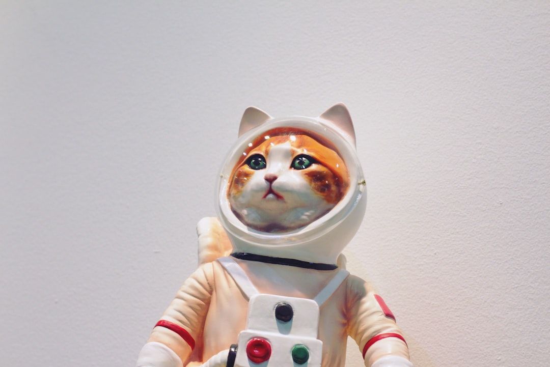 Eine Katzenfigur in einem weißen Astronautenanzug mit durchsichtigem Helm, die vor einem schlichten Hintergrund stolz posiert, als sei sie bereit für ein Abenteuer am Himmel über Aachen.