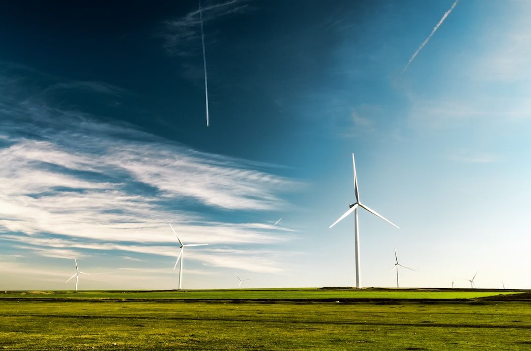 Windräder auf einer Wiese bei Aachen, unter einem Himmel mit vereinzelten Wolken und Kondensstreifen.