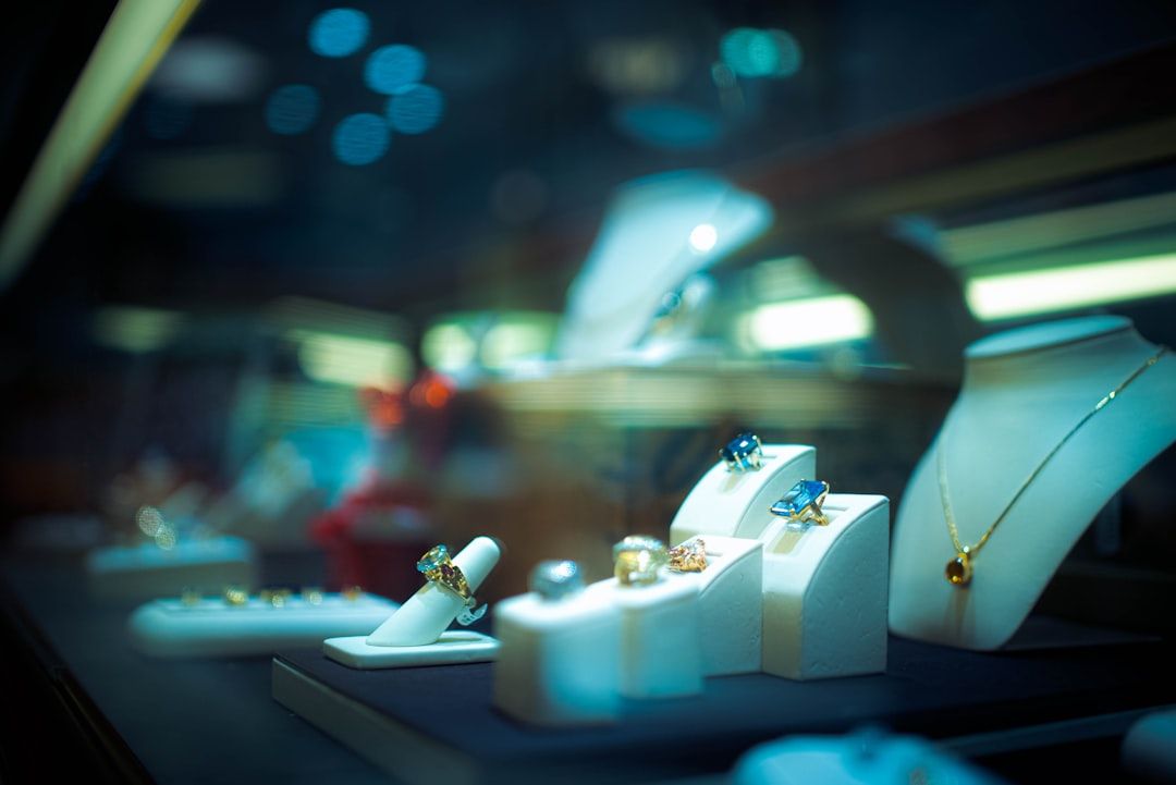 Eine Schmuckvitrine präsentiert Ringe und Halsketten auf Ständern unter raffinierter Beleuchtung und erinnert an die Eleganz der berühmten Aachener Boutiquen.
