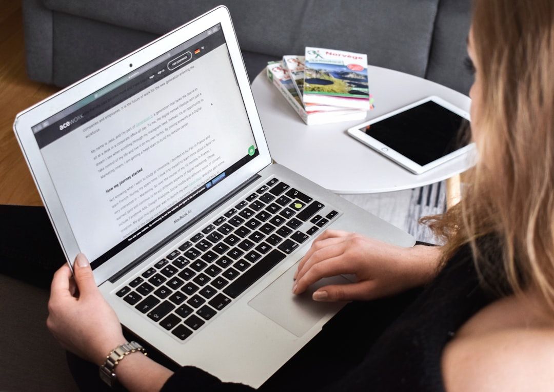 Eine Person sitzt an einem Tisch und liest auf ihrem Laptop einen Artikel über Aachen. Daneben liegen ein Tablet und ein paar Bücher.