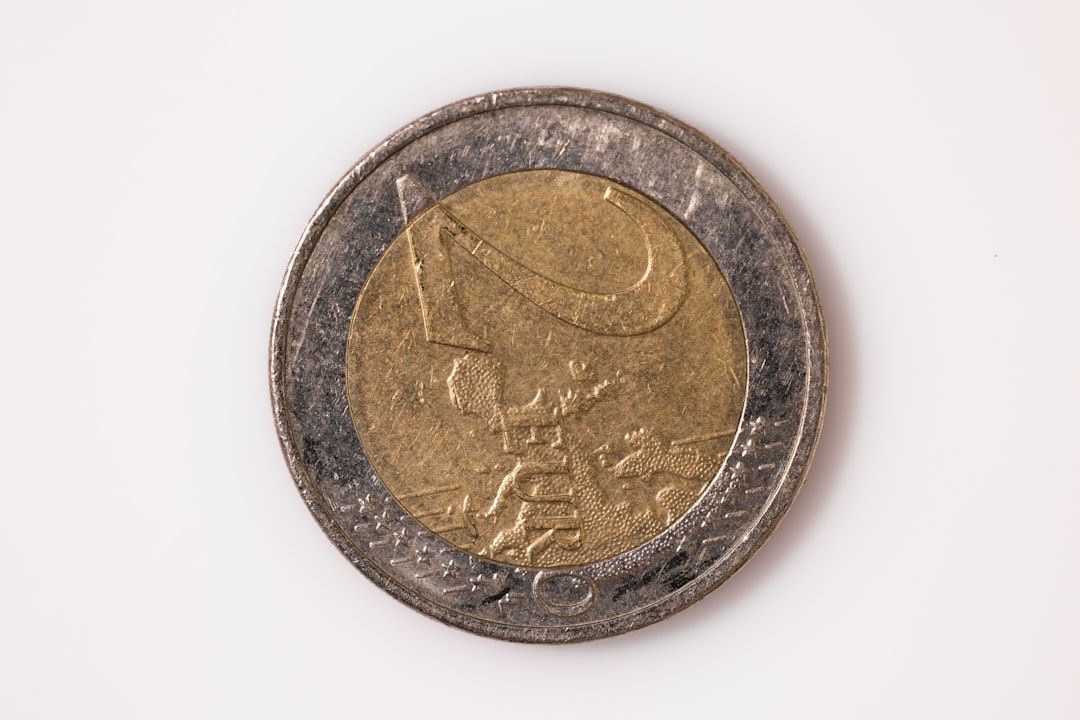 Eine Nahaufnahme einer 1-Euro-Münze auf weißem Hintergrund. Die Münze, die an die reiche Geschichte Aachens erinnert, hat eine goldfarbene Mitte und einen silberfarbenen Außenring mit dem Euro-Symbol und einer Europakarte.