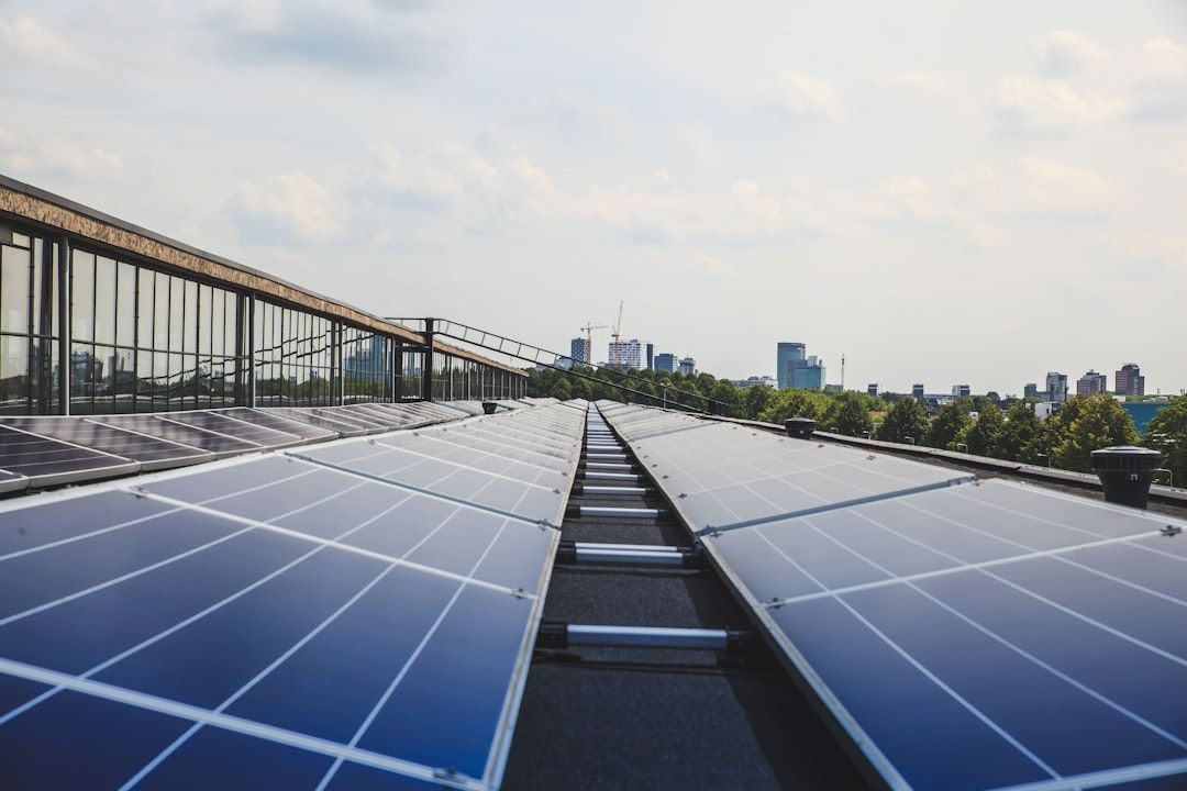 Reihen von Solarmodulen auf dem Dach eines Gebäudes mit der Skyline von Aachen im Hintergrund.