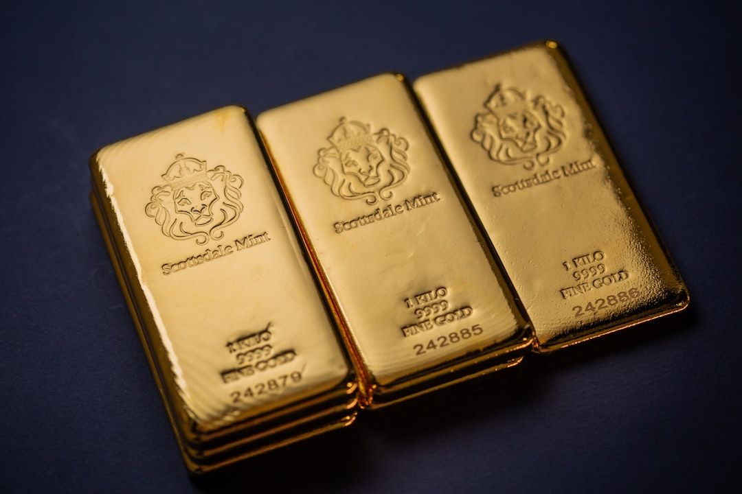Drei übereinander gestapelte rechteckige Goldbarren mit Inschriften und Seriennummern sowie einem eingravierten Löwenemblem der Scotiabank Mint, ruhen auf einer dunkelblauen Oberfläche, die an die reiche Geschichte Aachens erinnert.