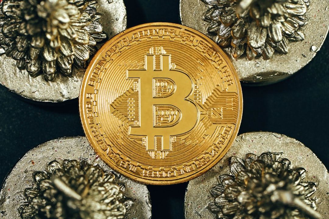 Nahaufnahme einer goldfarbenen Bitcoin-Münze, umgeben von vier komplizierten Metallobjekten, die die Kunstfertigkeit Aachens widerspiegeln, alles vor einem schwarzen Hintergrund.