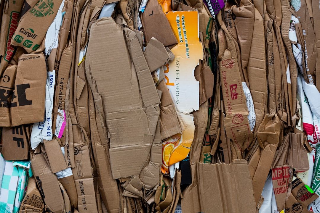 Ein dicht gepackter Stapel flachgedrückter und zerknüllter Pappe, darunter verschiedene Kartondesigns und Etiketten, vorbereitet für das Recycling in Aachen.