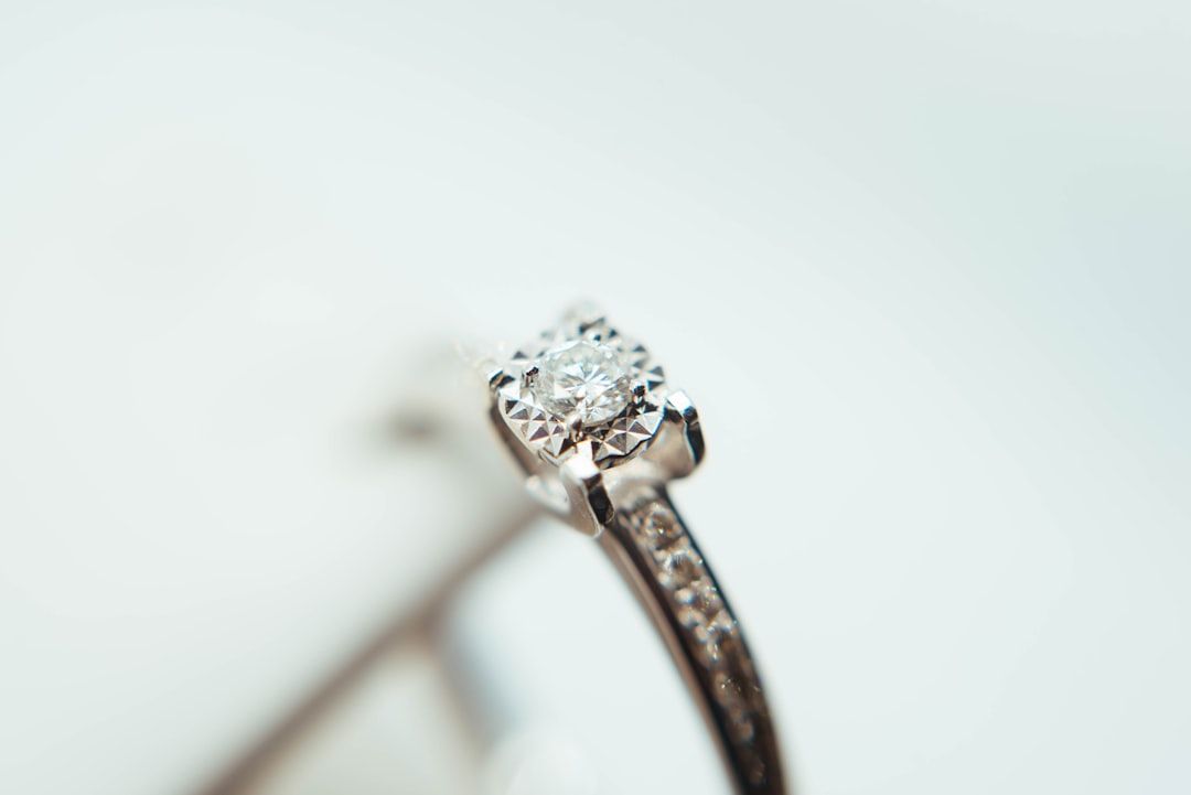 Eine Nahaufnahme eines Diamantrings mit einem Solitärdiamanten in einer Krappenfassung, die an die Eleganz der historischen Schätze Aachens erinnert, vor einem strahlend weißen Hintergrund.