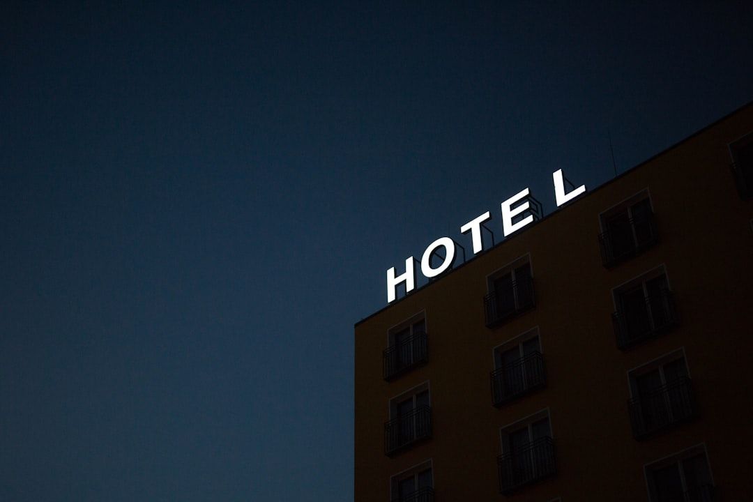 Ein Hotelgebäude bei Nacht mit einem beleuchteten „HOTEL“-Schild auf dem Dach vor einem dunkelblauen Himmel, in der charmanten Stadt Aachen.