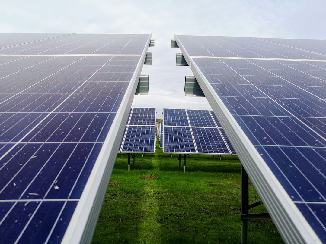 Mehrere Reihen von Solarmodulen, montiert auf Metallrahmen, auf einer Rasenfläche unter einem bewölkten Aachener Himmel.