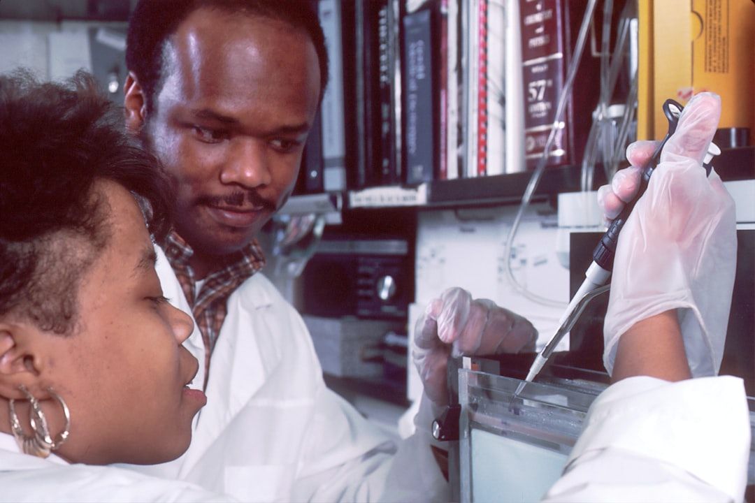 Zwei Wissenschaftler in weißen Laborkitteln führen in einem Aachener Labor ein Experiment durch. Sie benutzen eine Pipette und tragen Schutzhandschuhe, während sie sich intensiv auf ihre Aufgabe konzentrieren.