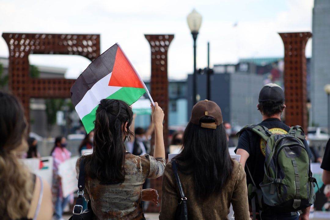 Eine Gruppe von Menschen hat sich bei einer öffentlichen Veranstaltung in Aachen versammelt, im Vordergrund steht eine Frau, die eine palästinensische Flagge hält.