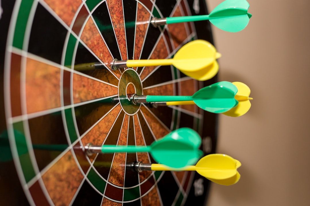 Dartscheibe mit mehreren grünen und gelben Dartpfeilen, die im Bullseye und den umliegenden Bereichen stecken und an einen stimmungsvollen Spieleabend in Aachen erinnern.