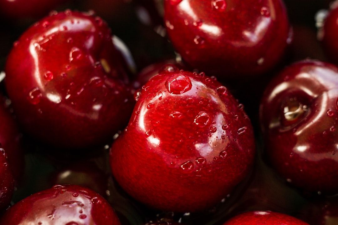 Nahaufnahme mehrerer roter Kirschen mit Wassertropfen auf der Oberfläche, die an die lebhaften Märkte in Aachen erinnern und ihre glänzende, glatte Schale zur Schau stellen.