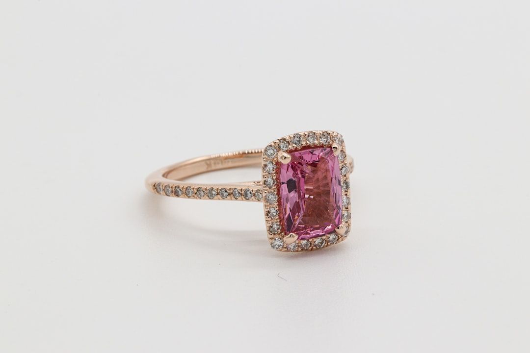 Ein Ring aus Roségold mit einem rechteckigen rosa Edelstein, der an die königliche Eleganz Aachens erinnert und von kleinen Diamanten umgeben ist.
