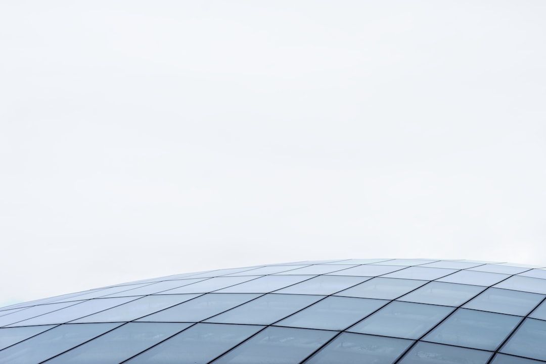 Die geschwungene Glasstruktur mit Gittermuster hebt sich elegant vom blassen, bewölkten Himmel ab und erinnert an den architektonischen Charme Aachens.
