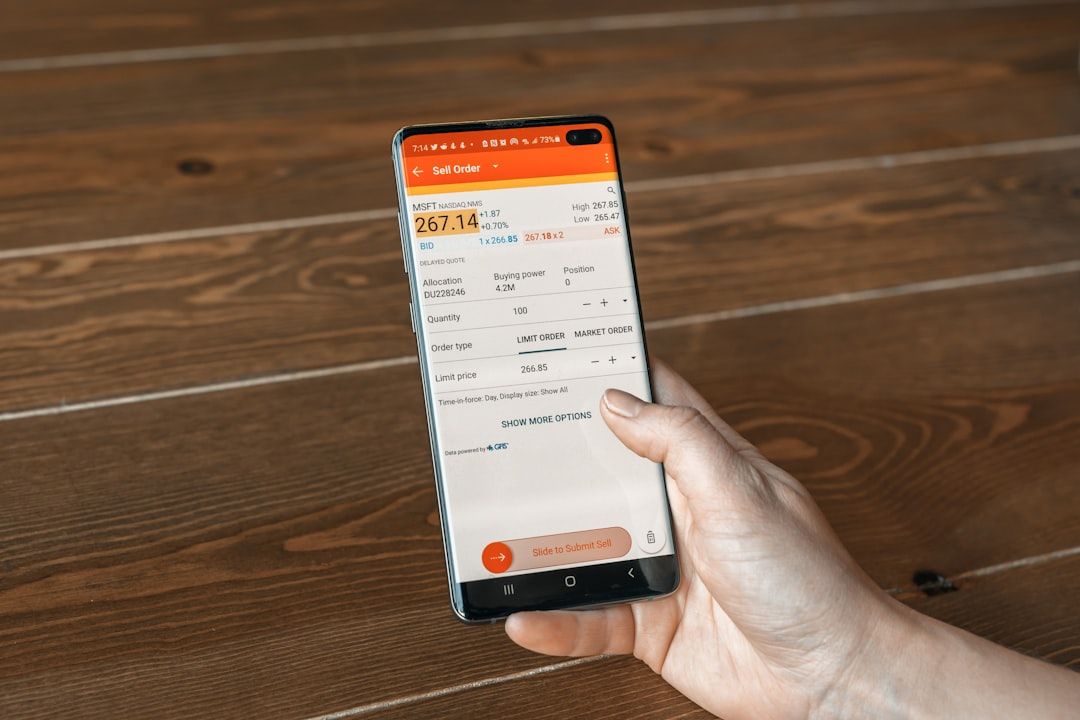 Eine Person in Aachen hält ein Smartphone in der Hand, auf dem die Oberfläche einer Aktienhandels-App mit den Details eines Verkaufsauftrags angezeigt wird.