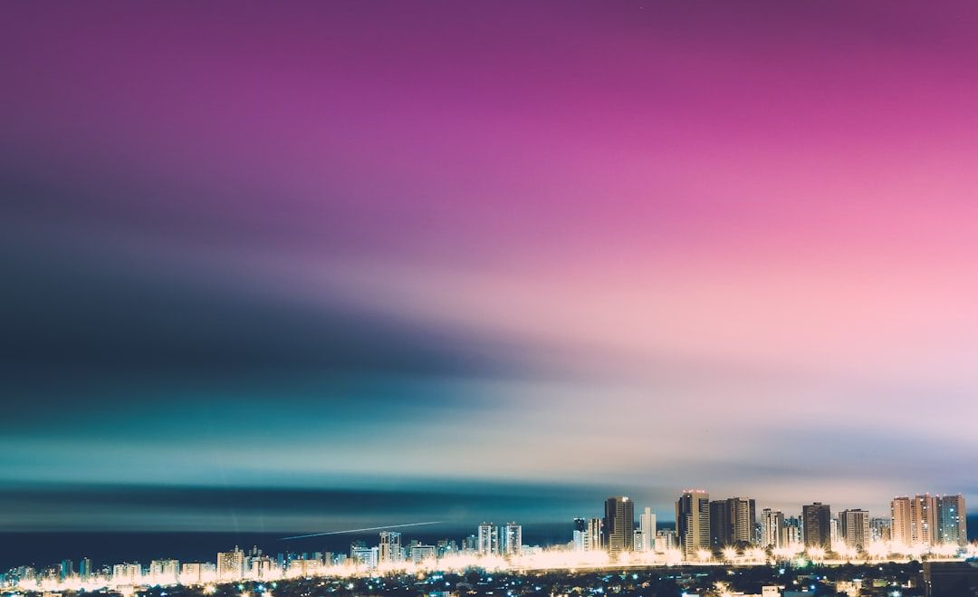 Die Skyline von Aachen in der Abenddämmerung mit ihren hohen, hell beleuchteten Gebäuden unter einem von Violett nach Blau wechselnden Himmel erzeugt ein atemberaubendes Stadtpanorama.
