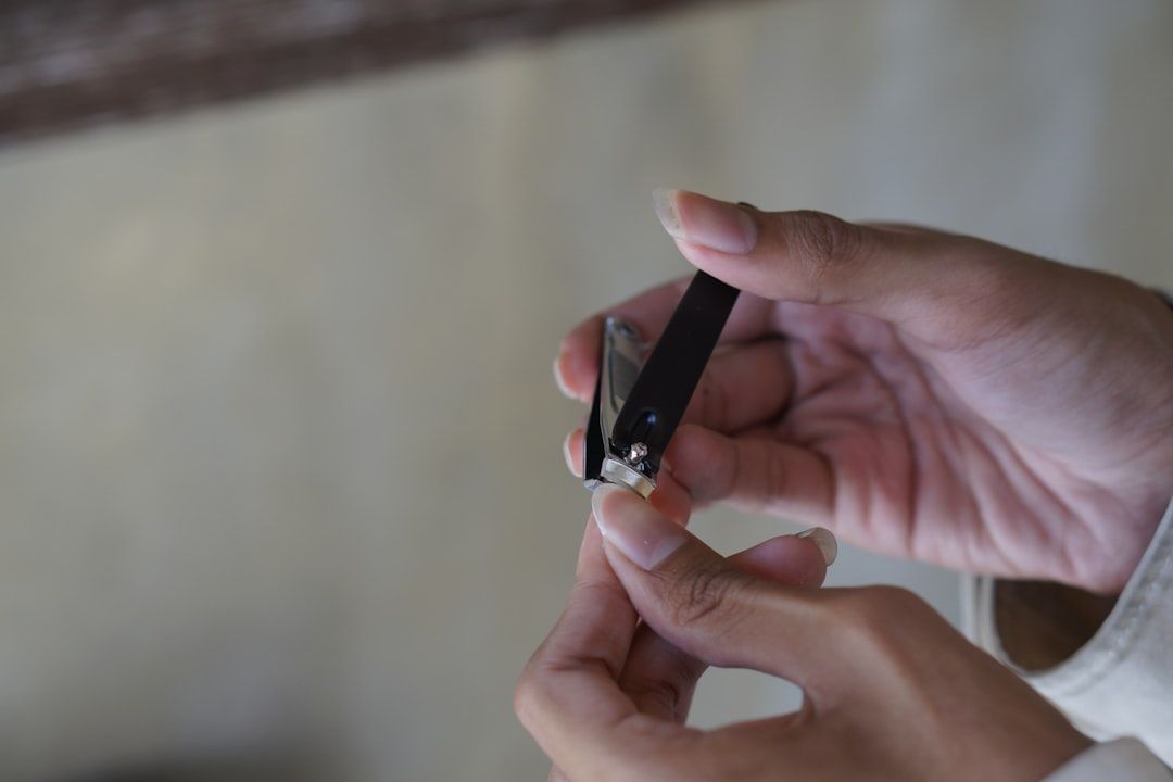 Eine Person mit hellbrauner Haut hält einen Nagelknipser und schneidet vorsichtig den Nagel ihres Daumens. Vielleicht bereitet sie sich auf einen langen Tag vor, an dem sie Aachen erkundet.