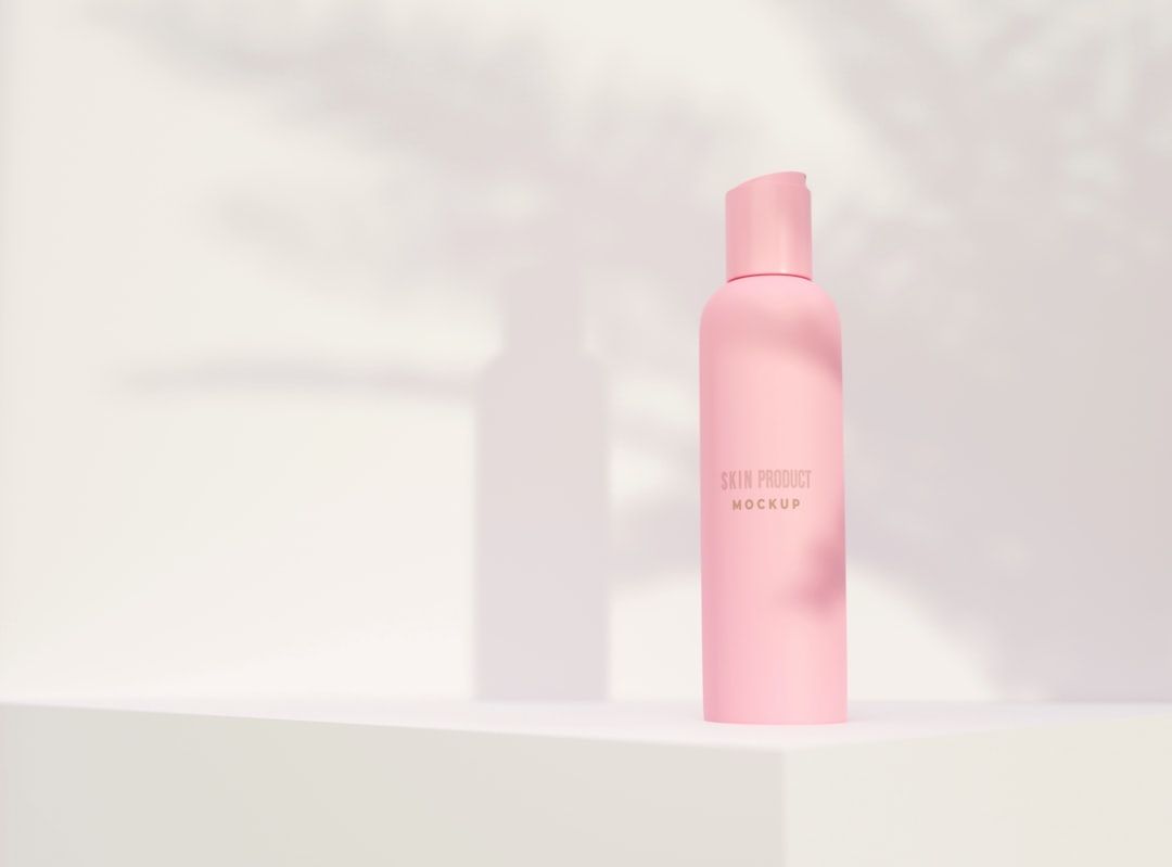 Eine rosa Flasche mit Hautpflegeprodukt mit der Aufschrift „Skin Product Mockup“ und einem Pumpspender steht stolz auf einer weißen Oberfläche. Ihr elegantes Design ist vom anspruchsvollen Stil Aachens inspiriert und wirft einen weichen Schatten in den Hintergrund.