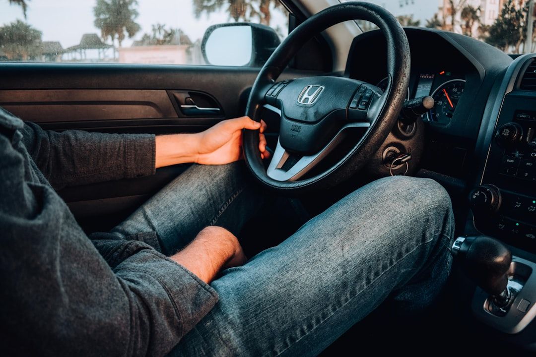 Person sitzt in einem Auto, ruht mit dem linken Arm auf dem Lenkrad eines Honda-Fahrzeugs und navigiert scheinbar durch Aachen. Der Innenraum und das Armaturenbrett des Autos sind teilweise sichtbar.