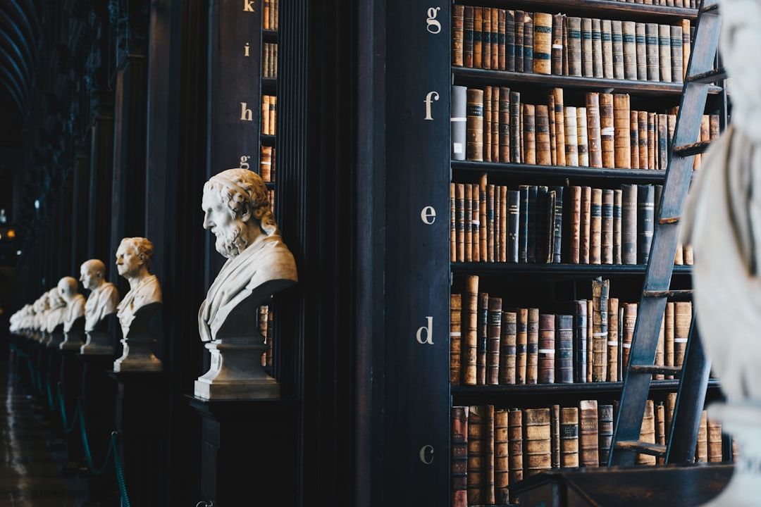Das Interieur einer Aachener Bibliothek mit Reihen von Bücherregalen voller Bücher, einer Leiter und in einer Reihe auf Sockeln ausgestellten Büstenskulpturen.