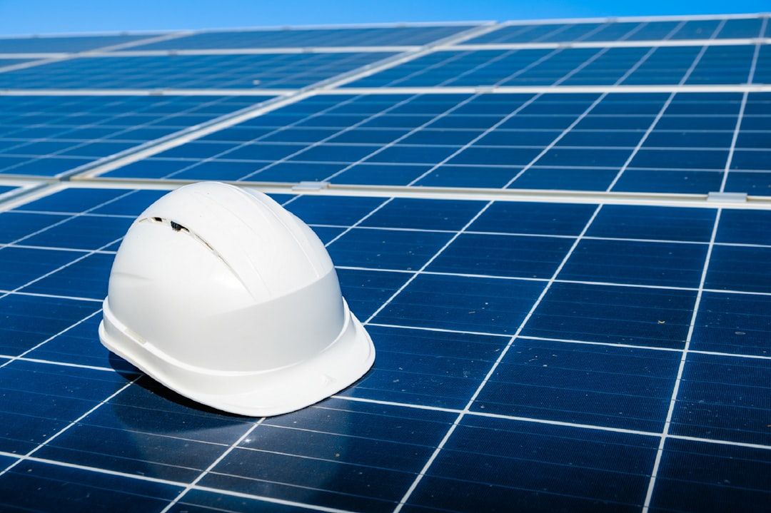 Ein weißer Bauhelm ruht auf einer Solarzellenanlage unter dem klaren blauen Himmel und erinnert an innovative Projekte in Aachen.
