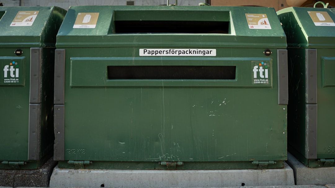 In Aachen steht neben weiteren ähnlichen Behältern eine grüne Recyclingtonne mit der Aufschrift „Pappersförpackningar“, die darauf hinweist, dass sie für Papierverpackungen bestimmt ist.