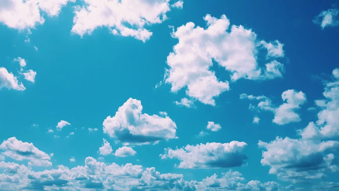 Strahlend blauer Himmel mit flauschigen weißen Wolken.