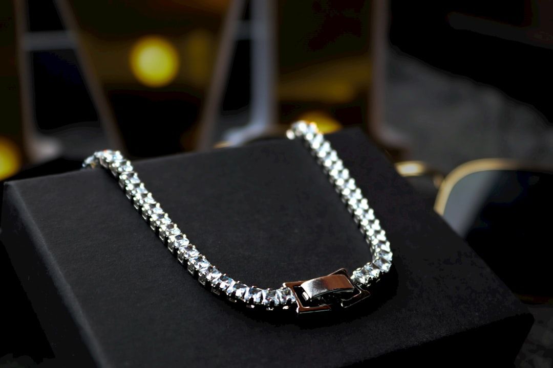 Silbernes Armband mit rechteckigem Verschluss auf einer schwarzen Box, mit unscharfer Hintergrundbeleuchtung, die an den eleganten Charme Aachens erinnert.