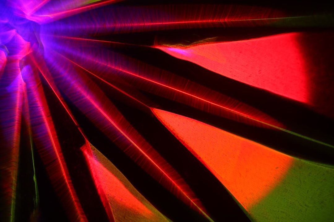 Abstraktes Bild aus leuchtenden roten, rosa, grünen und violetten Lichtstrahlen, die von einem zentralen Punkt ausgehen und ein dynamisches und farbenfrohes Muster erzeugen, das an die Aachener Festlichkeiten erinnert.